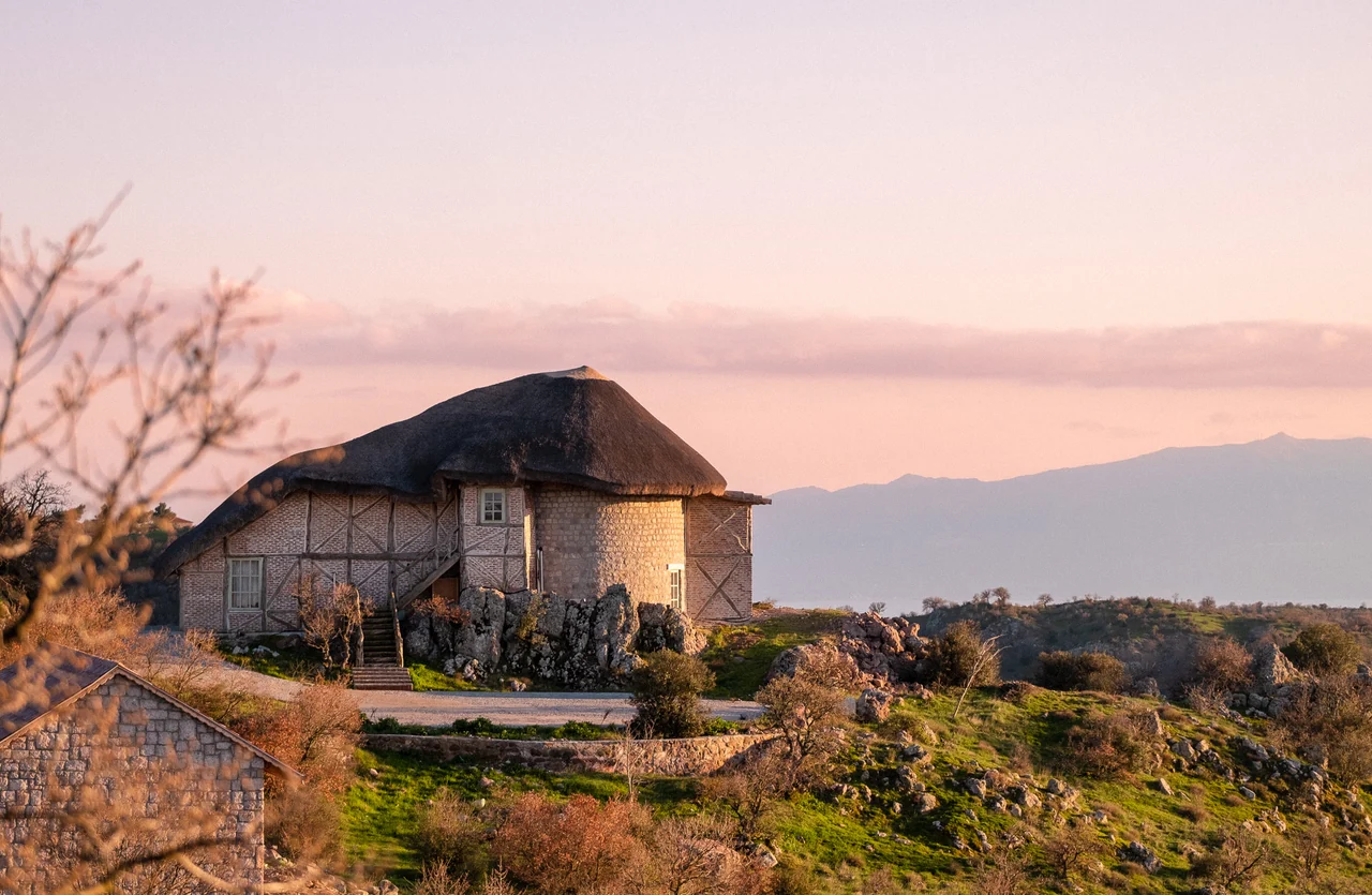 A thatched stone house at Manici Çiftlik at sunset, the Kaz Mountains behind